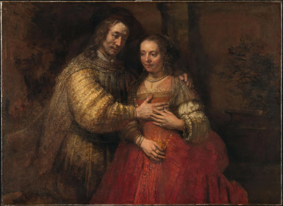 Rembrandt painting of Isaac and Rebecca in a tender embrace, wearing richly textured gold, red, and brown clothing against a dark ground.
